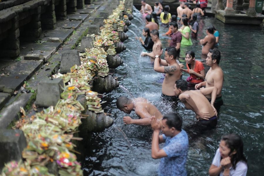 Traditional Balinese water temple with stone carvings and tropical gardens