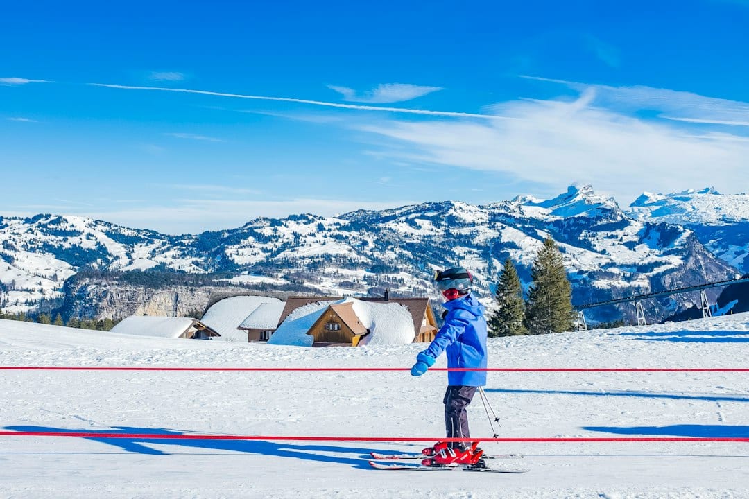 A beginner skier learning on a gentle snowy slope with an instructor nearby