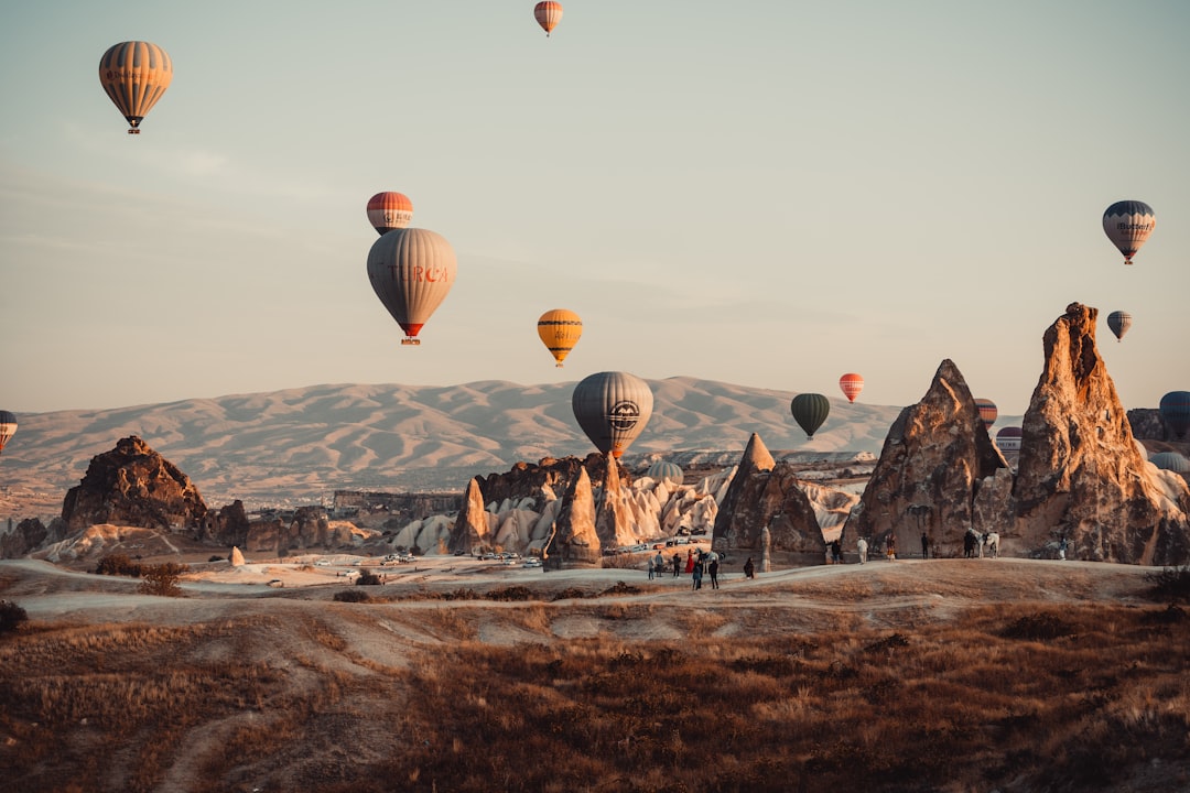 Colorful hot air balloons floating over Cappadocia's unique rock formations at sunrise