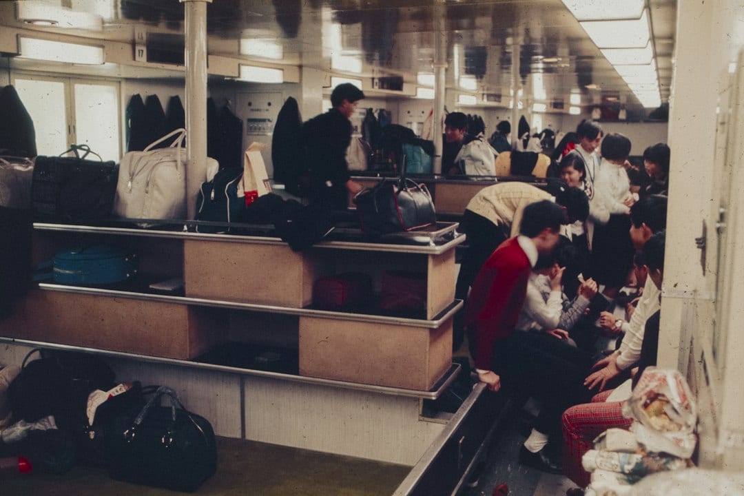 Cruise ship embarkation terminal with passengers checking in and porters handling luggage