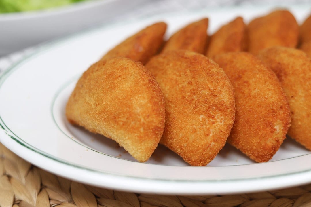 Golden brown empanadas arranged on a white plate