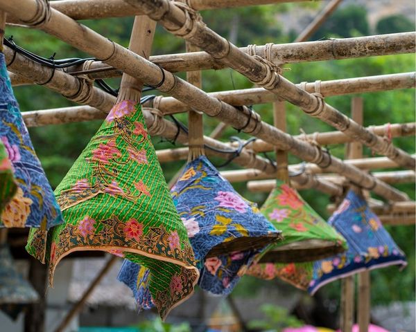 Colorful woven hats and traditional Hmong textiles hanging in a Northern Thailand hill tribe village