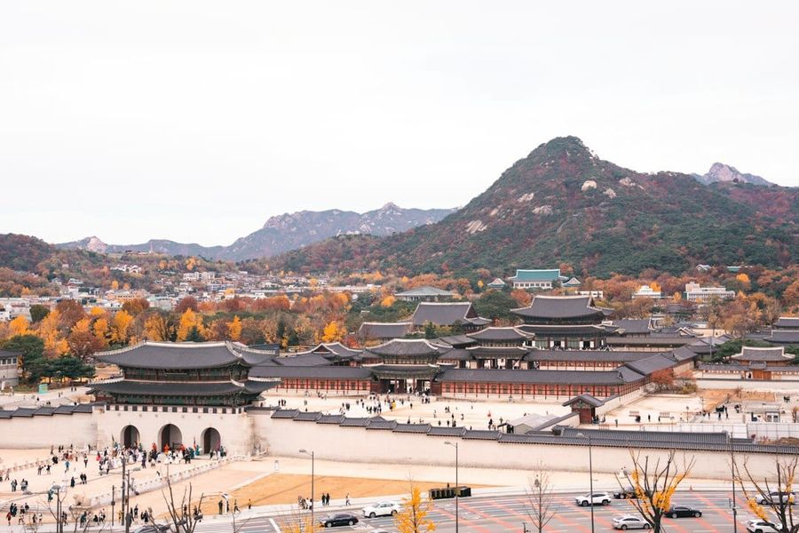 Gyeongbokgung Palace in Seoul framed by vibrant red and orange autumn maple trees, a must-see stop on a 2026 South Korea autumn foliage itinerary
