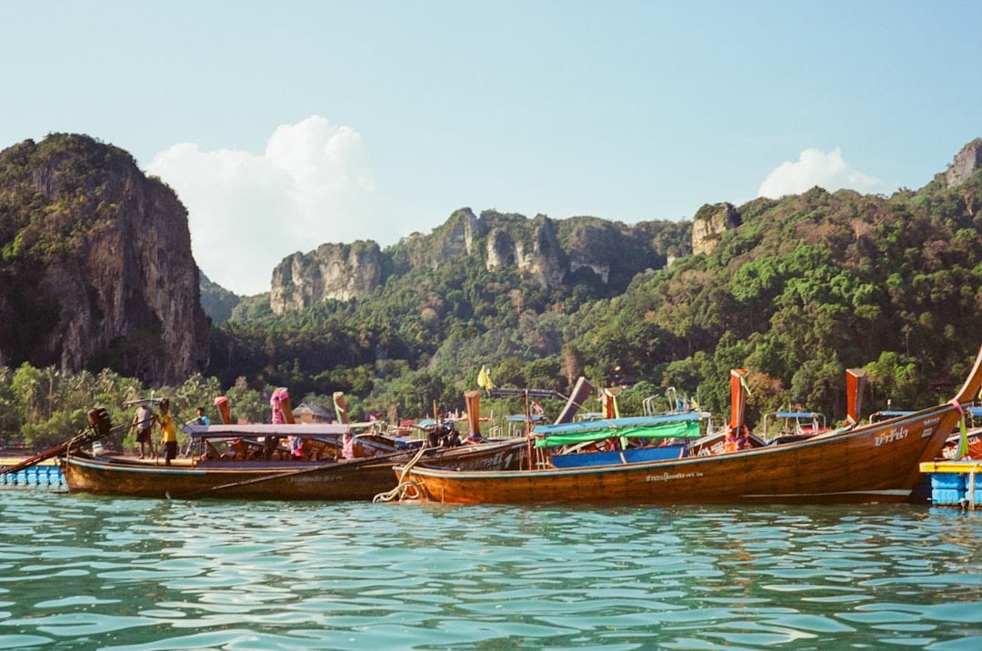 Longtail boats float on turquoise water near mountains