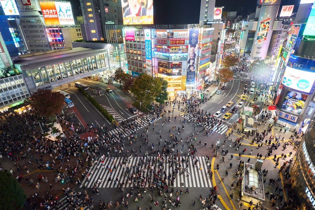 Shibuya crossing in Tokyo with neon lights and crowds at dusk