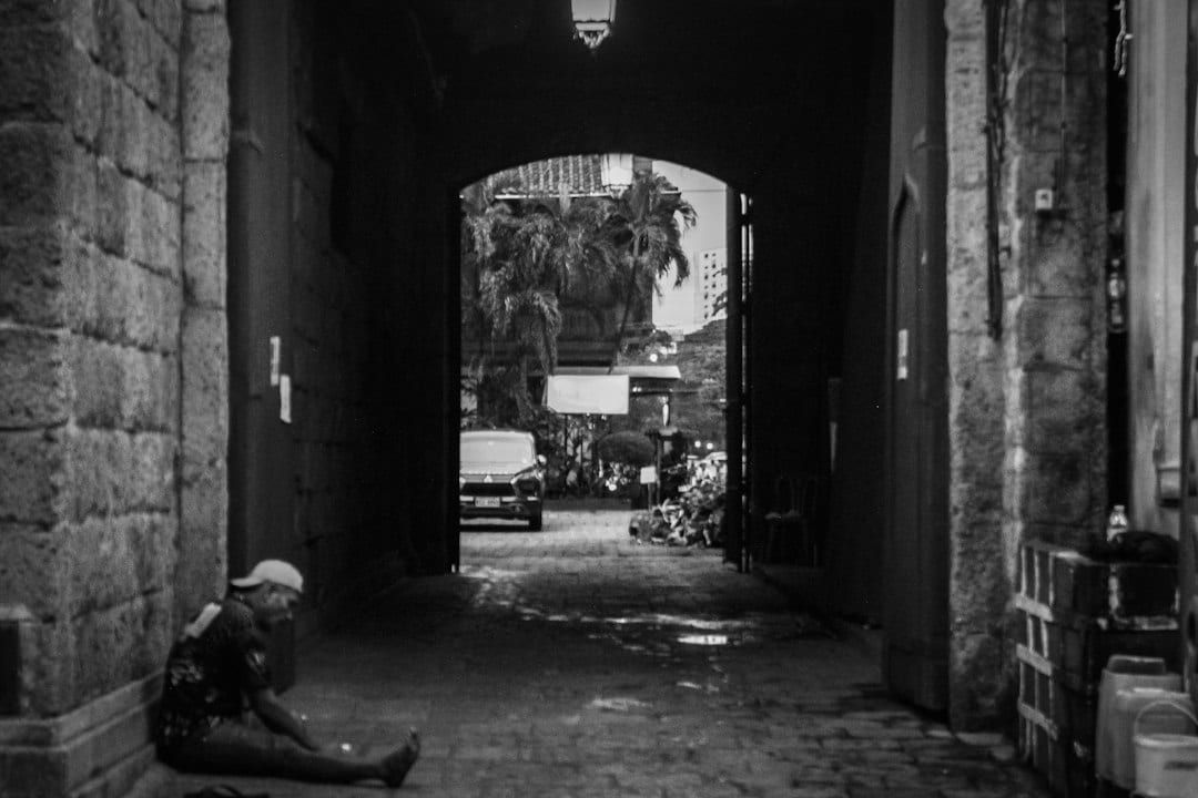 Cobblestone street of Calle Crisologo in Vigan with colonial stone houses and a person resting in an archway